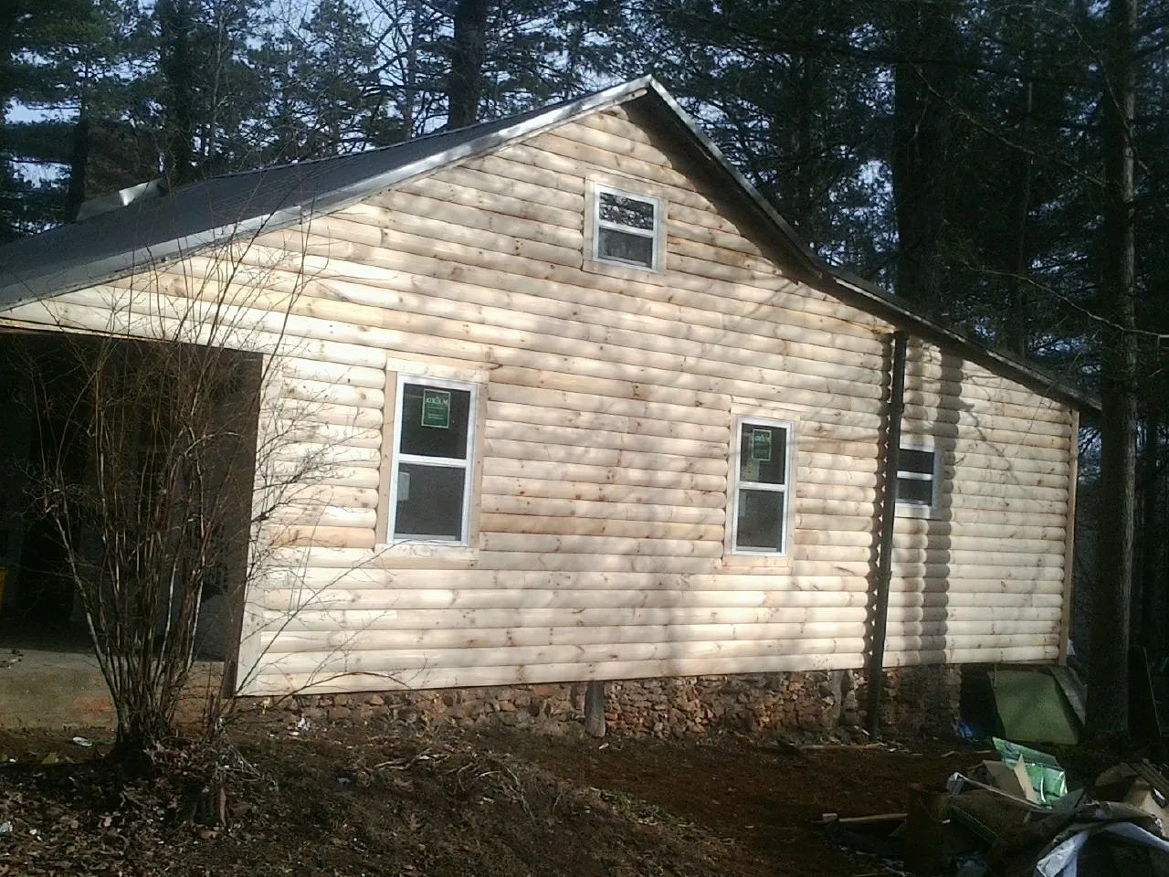 New log siding and dark metal roofing on a gable end in Glenwood