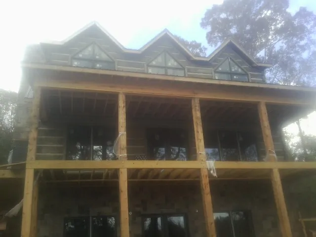 Dormers and porch framing on a large log home under construction — Roof Coating work by our crew in Glenwood